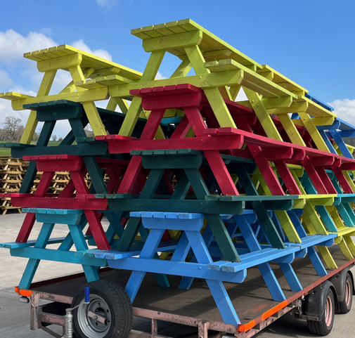 Brightly coloured picnic tables stacked on a trailer